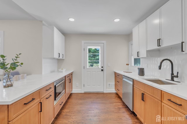kitchen featuring stainless steel appliances, a sink, light wood-style flooring, light countertops, and a peninsula