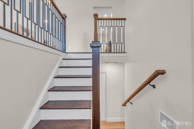 stairs featuring a high ceiling, wood finished floors, and baseboards