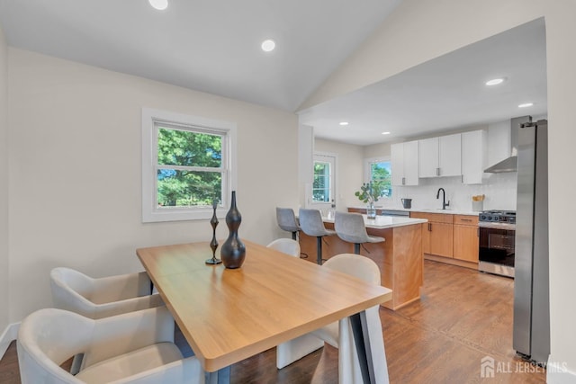 dining space with light wood-style flooring, lofted ceiling, and recessed lighting