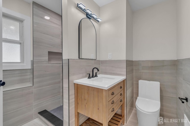 bathroom with tile walls, vanity, and toilet