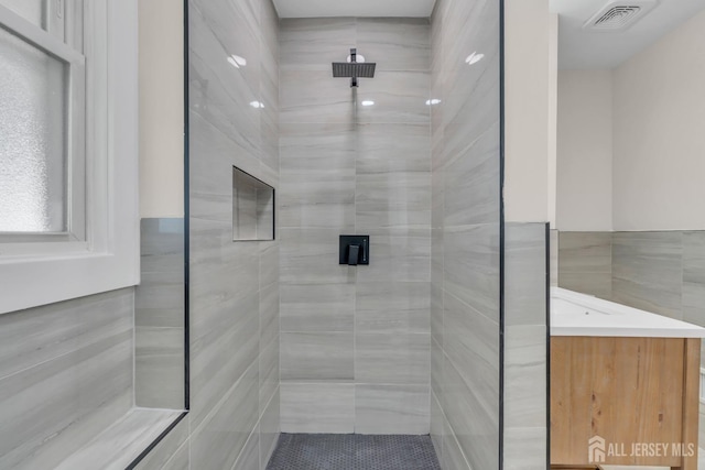 full bath with tiled shower and tile walls