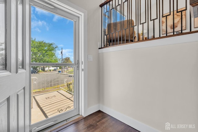doorway to outside with dark wood-style floors and baseboards