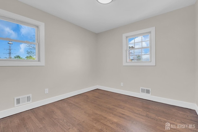 spare room featuring baseboards and dark wood-type flooring