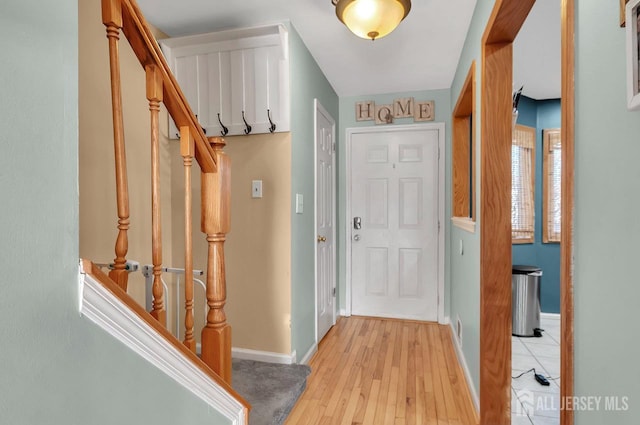 foyer entrance with visible vents, baseboards, light wood-style flooring, and stairs