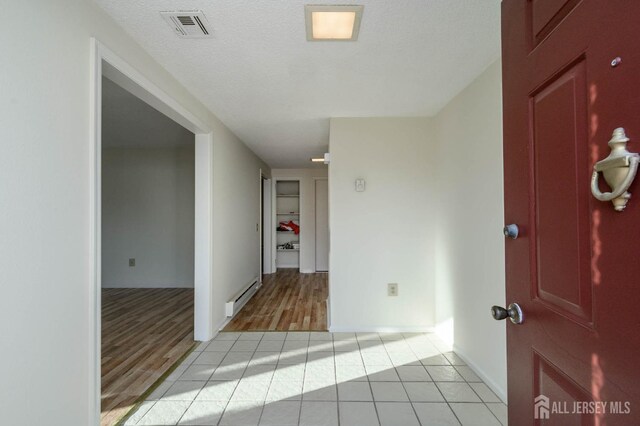 tiled empty room with a textured ceiling and a baseboard radiator