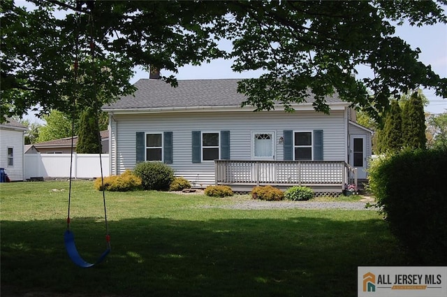 view of front facade with a deck, fence, and a front lawn