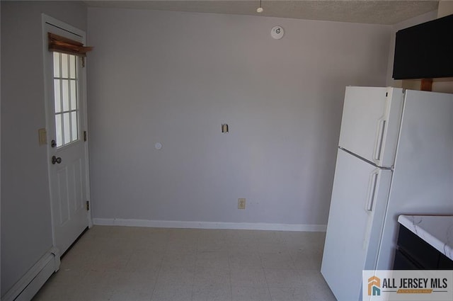 kitchen with freestanding refrigerator, light floors, baseboard heating, and light countertops