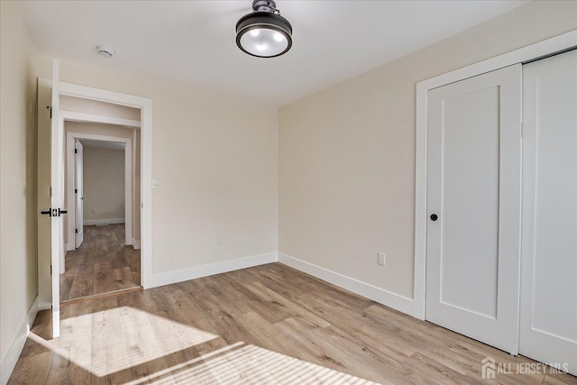 unfurnished bedroom featuring light wood-type flooring and a closet