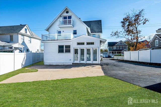 rear view of property featuring a balcony and a lawn