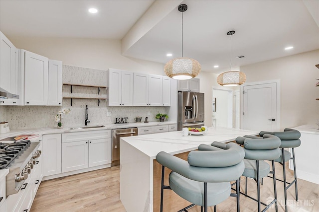 kitchen featuring a center island, white cabinetry, stainless steel appliances, sink, and hanging light fixtures