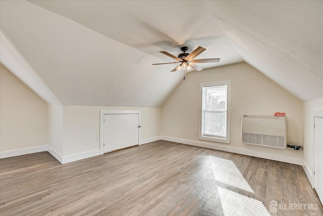 additional living space with ceiling fan, heating unit, lofted ceiling, and light wood-type flooring