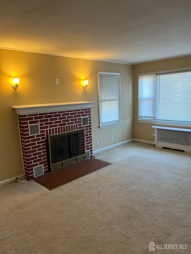 unfurnished living room with visible vents, carpet flooring, a fireplace, and radiator heating unit