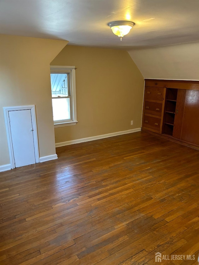 bonus room featuring baseboards, dark wood-style flooring, and vaulted ceiling