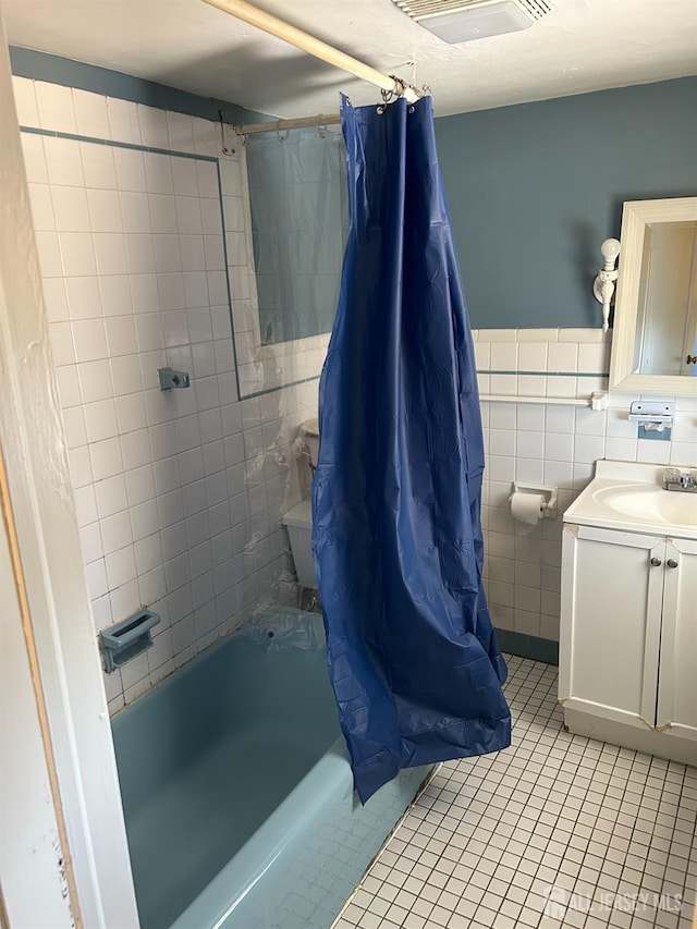 bathroom featuring vanity, shower / bathtub combination with curtain, visible vents, tile patterned floors, and tile walls