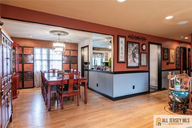 dining space with a wainscoted wall, light wood-type flooring, an inviting chandelier, and recessed lighting