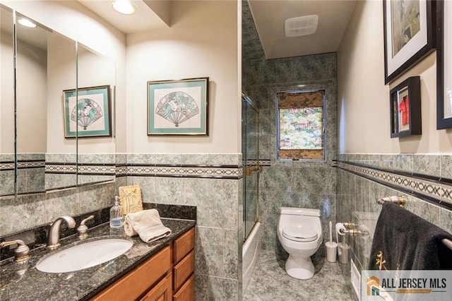 bathroom featuring enclosed tub / shower combo, tile patterned floors, a wainscoted wall, toilet, and tile walls