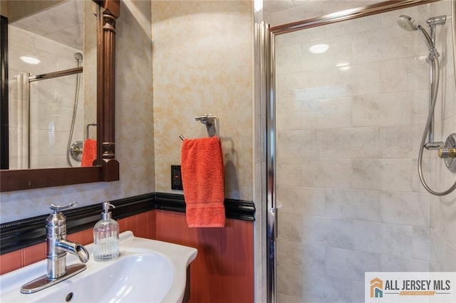 bathroom featuring wainscoting, a sink, and a stall shower