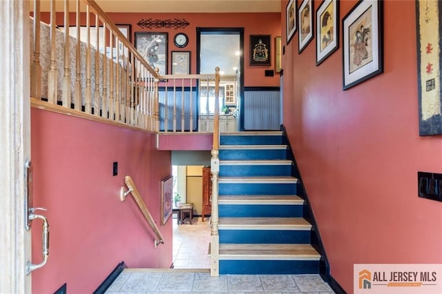 stairway featuring tile patterned flooring and a high ceiling