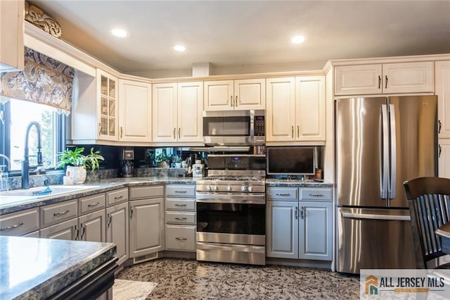 kitchen with gray cabinets, recessed lighting, glass insert cabinets, stainless steel appliances, and a sink