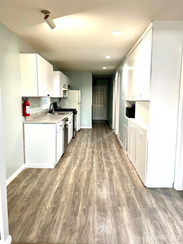 kitchen featuring white cabinetry, stainless steel dishwasher, white refrigerator, and light wood-type flooring