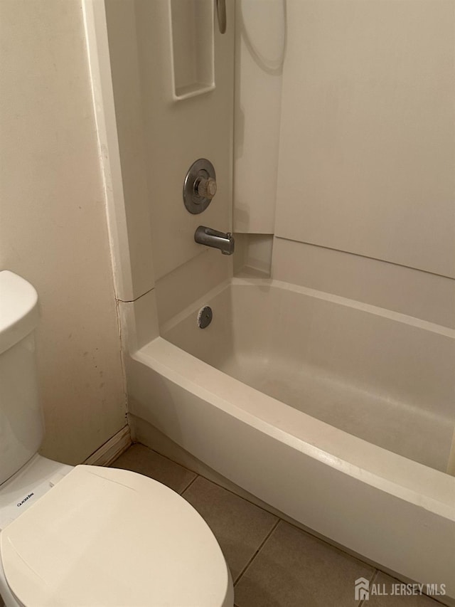 bathroom featuring tile patterned flooring, toilet, and bathing tub / shower combination