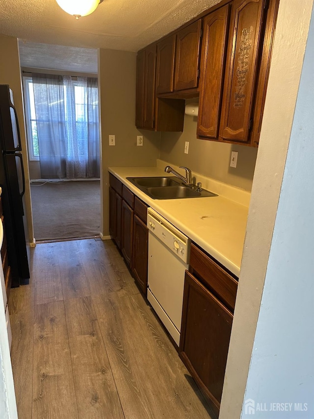 kitchen with sink, light hardwood / wood-style flooring, refrigerator, white dishwasher, and a textured ceiling