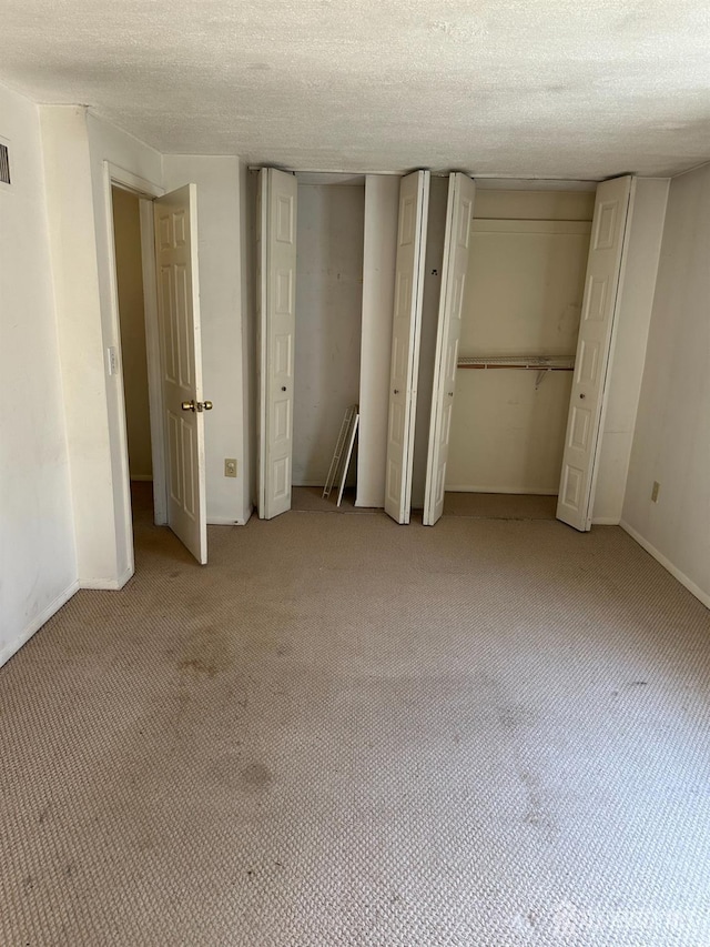 unfurnished bedroom featuring a textured ceiling and light colored carpet