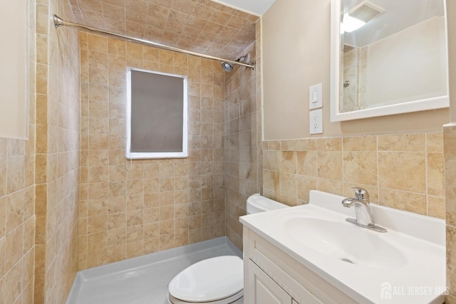 full bathroom with visible vents, tiled shower, toilet, vanity, and tile walls