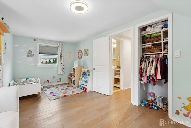 bedroom featuring light wood-type flooring, a closet, lofted ceiling, and baseboards