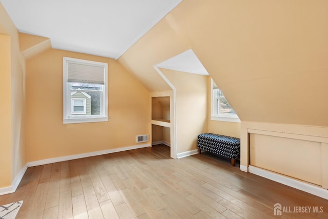 bonus room with visible vents, lofted ceiling, light wood-style flooring, and baseboards