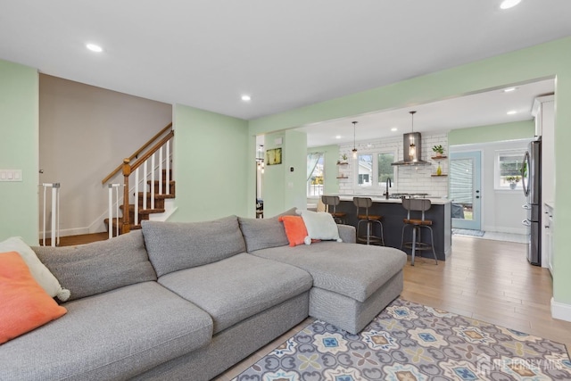 living area featuring light wood-type flooring, baseboards, recessed lighting, and stairs