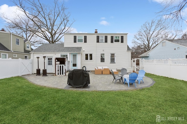 rear view of property featuring a lawn, a patio area, a fenced backyard, and a gate