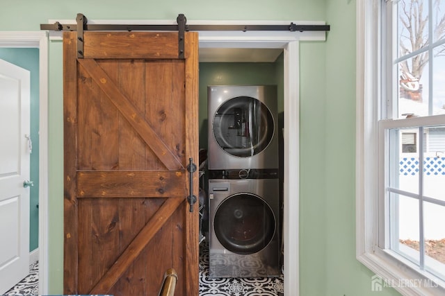 washroom with stacked washer / dryer, laundry area, and a barn door