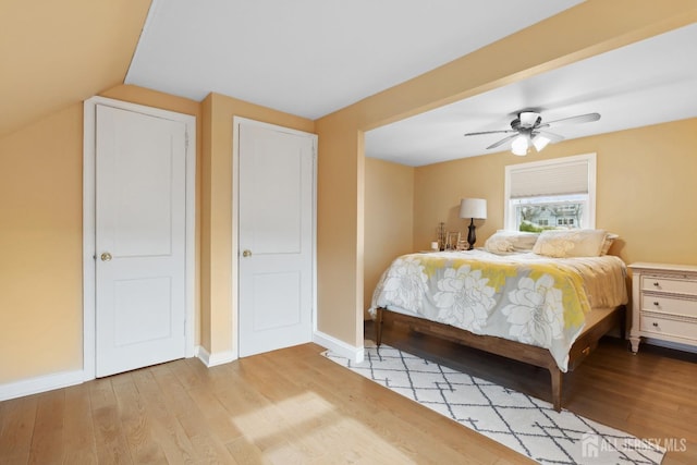 bedroom featuring light wood-style floors, baseboards, vaulted ceiling, and a ceiling fan