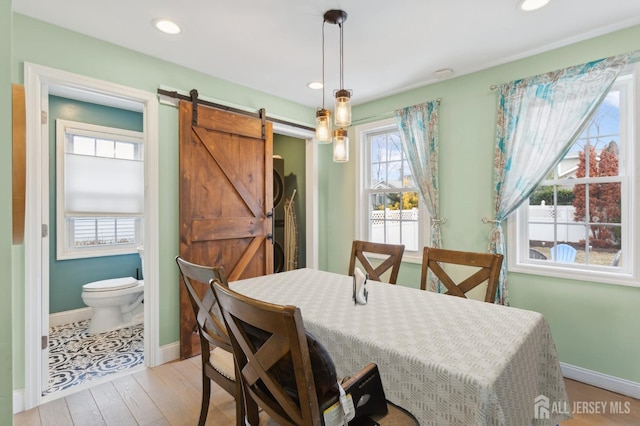 dining space featuring light wood-type flooring, a barn door, baseboards, and recessed lighting