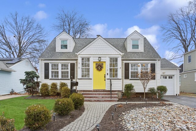 cape cod-style house with a garage and a front lawn