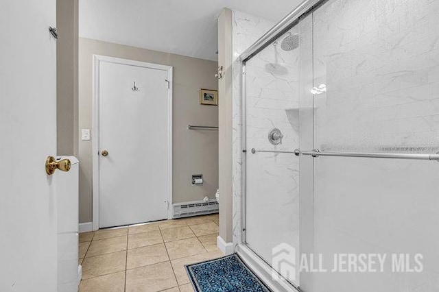 bathroom with tile patterned flooring, a shower stall, baseboards, and baseboard heating