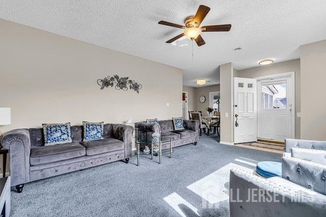 living room featuring visible vents, carpet, a ceiling fan, and a textured ceiling