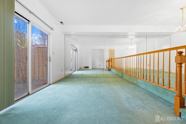 carpeted spare room with an inviting chandelier