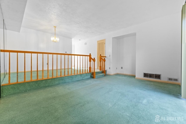 empty room with carpet flooring, a notable chandelier, and a textured ceiling