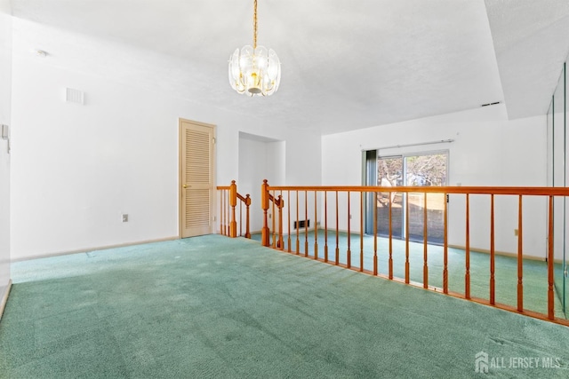 carpeted spare room with a notable chandelier