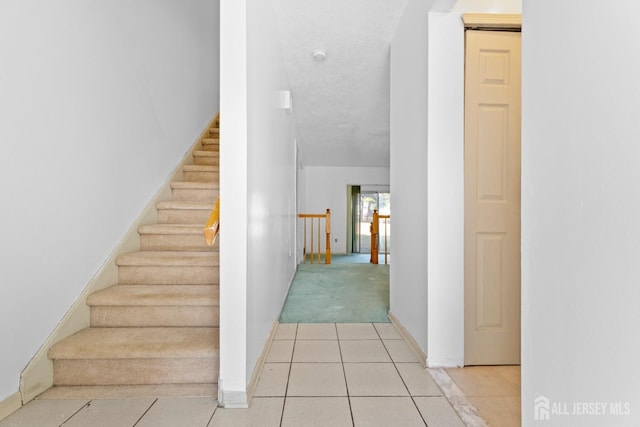 stairway featuring tile patterned floors and a textured ceiling