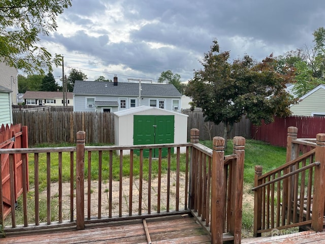 wooden terrace featuring a storage unit and a yard