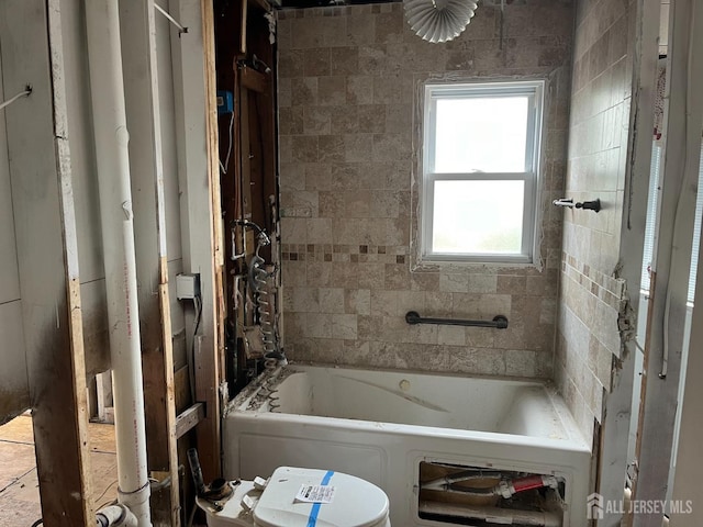 bathroom with a tub to relax in and toilet