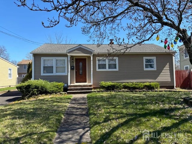 view of front facade with entry steps, fence, and a front yard