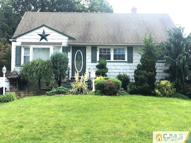 view of front of house featuring a shingled roof, a chimney, and a front yard