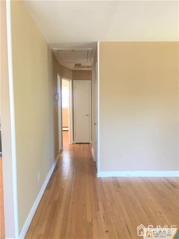 hall with baseboards, a baseboard heating unit, and light wood-style floors