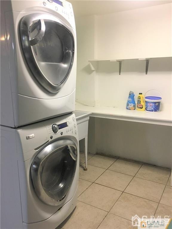 laundry room featuring laundry area, light tile patterned floors, and stacked washer and clothes dryer