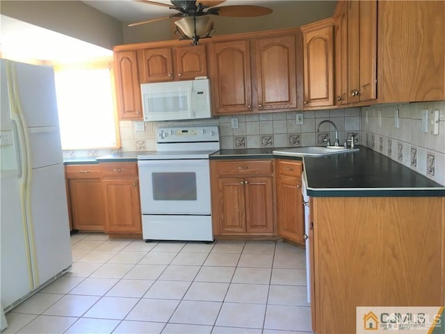 kitchen featuring white appliances, brown cabinetry, and a sink