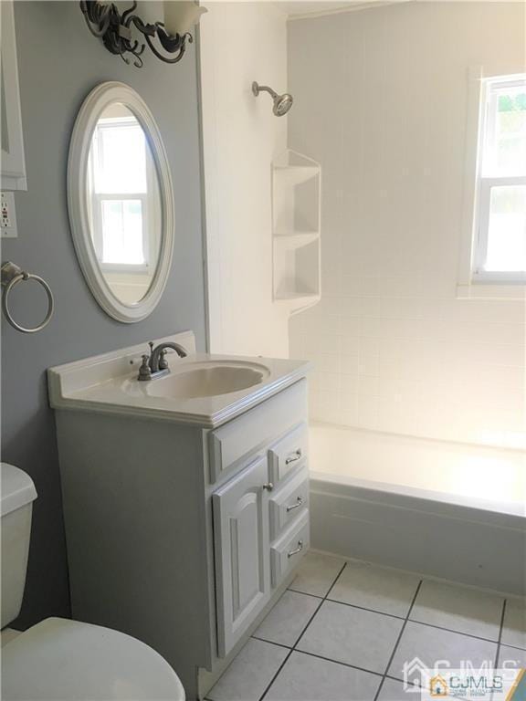 bathroom with toilet, tile patterned flooring, a wealth of natural light, and vanity